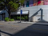 a street corner with an empty sidewalk and a building in the background with a billboard over the sidewalk that reads blue