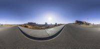 an angle view of the sun as seen from a ramp in a parking lot with a dirt road and mountains in the background