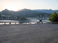 a car parked at the edge of a road near a marina and mountains in background