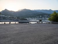 a car parked at the edge of a road near a marina and mountains in background