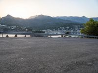 a car parked at the edge of a road near a marina and mountains in background