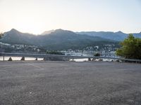 a car parked at the edge of a road near a marina and mountains in background