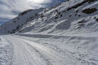 a person on skis on a snowy road with mountains in the background, and lots of snow all around