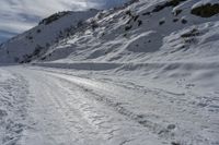 a person on skis on a snowy road with mountains in the background, and lots of snow all around