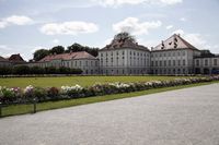 the large palace building is outside of a park area, with a paved road in front