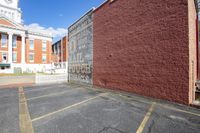 a brick wall in the middle of a parking lot with a clock tower in the background