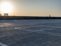 empty parking spaces in an industrial parking lot at sunset time with skyline in background,