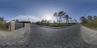 360 lens photo of the road and trees in a rural location with an arch for the entrance