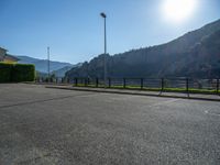 a parking lot with a fence and mountain in the background on a bright sunny day