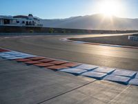 a photo of a dirt race track with sun setting in the distance of the track