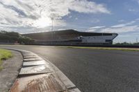 the sun shines through clouds over a race track and racetrack with concrete blocks in foreground