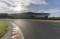 the sun shines through clouds over a race track and racetrack with concrete blocks in foreground