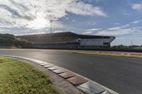 the sun shines through clouds over a race track and racetrack with concrete blocks in foreground