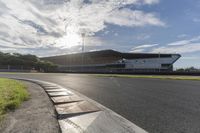 the sun shines through clouds over a race track and racetrack with concrete blocks in foreground