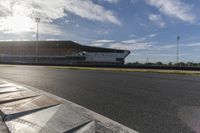 the sun shines through clouds over a race track and racetrack with concrete blocks in foreground