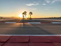 a photo of a dirt race track with sun setting in the distance of the track