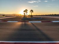 a photo of a dirt race track with sun setting in the distance of the track