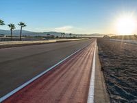 a photo of a dirt race track with sun setting in the distance of the track