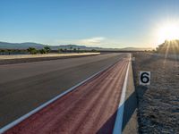 a photo of a dirt race track with sun setting in the distance of the track