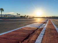 a photo of a dirt race track with sun setting in the distance of the track