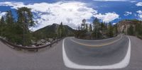 the view from a fish eye lens shows a curve in the road as clouds float by