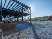 a picture of a building being built on a field near a forest in the background