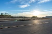 a motorcycle rider on a highway as the sun sets in the distance in the background