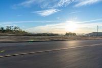 a motorcycle rider on a highway as the sun sets in the distance in the background