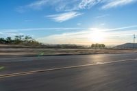 a motorcycle rider on a highway as the sun sets in the distance in the background