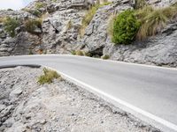 an empty road beside a rocky cliff on a sunny day or night near to town