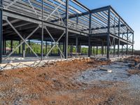 a picture of a building being built on a field near a forest in the background