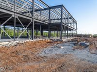 a picture of a building being built on a field near a forest in the background