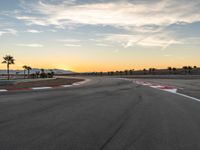 a photo of a dirt race track with sun setting in the distance of the track