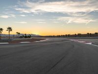 a photo of a dirt race track with sun setting in the distance of the track