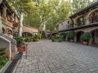 the courtyard and entry to a large home with trees in it's foreground