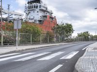 a street lined with traffic near a city ship on a cloudy day, with tall clouds