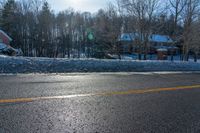 a stop sign stands on the side of a road near a snow covered area and some trees