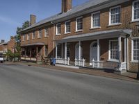 an old brick building sitting next to two rows of houses on a street with cars parked on it