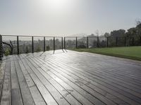 a wooden deck with a black railing next to a field and a soccer field in the background