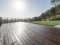 a wooden deck with a black railing next to a field and a soccer field in the background