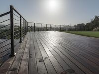 a wooden deck with a black railing next to a field and a soccer field in the background