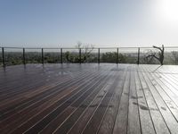 a wooden deck with a black railing next to a field and a soccer field in the background