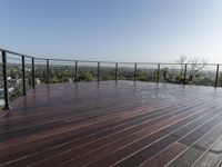 a wooden deck with a black railing next to a field and a soccer field in the background