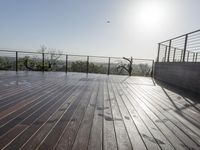 a wooden deck with a black railing next to a field and a soccer field in the background