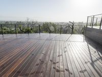 a wooden deck with a black railing next to a field and a soccer field in the background