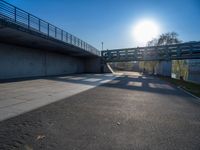 a skateboarder riding on a cement ramp next to a city street under a bridge