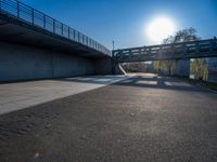 a skateboarder riding on a cement ramp next to a city street under a bridge