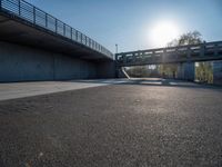 a skateboarder riding on a cement ramp next to a city street under a bridge