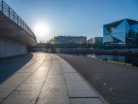 a skateboarder riding on a cement ramp next to a city street under a bridge