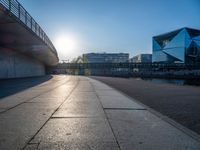 a skateboarder riding on a cement ramp next to a city street under a bridge